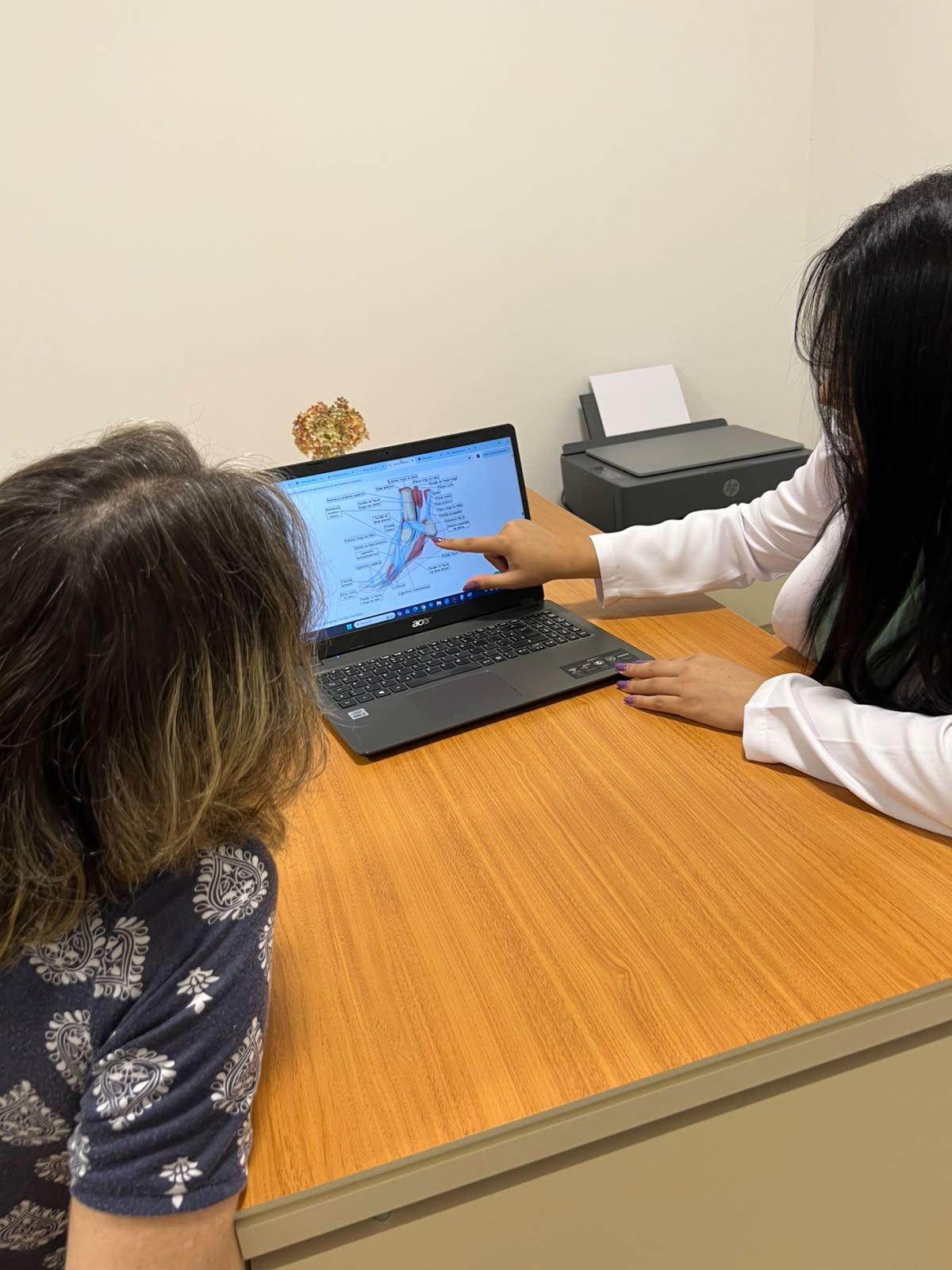 Dra. Nayanne Braga em consulta, explicando anatomia para paciente